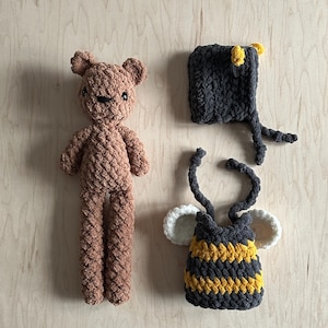 May include: A brown crocheted teddy bear, a black and yellow crocheted bee costume, and a black crocheted bee hat with yellow accents.