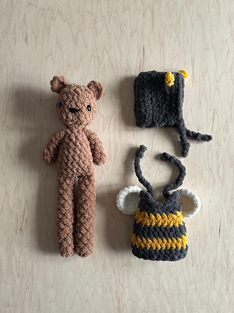 May include: A brown crocheted teddy bear, a black and yellow crocheted bee costume, and a black crocheted bee hat with yellow accents.