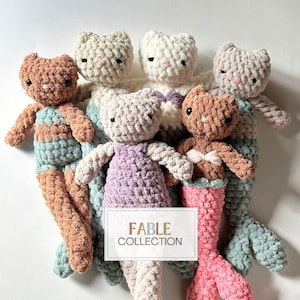 May include: Six crocheted mermaid cat toys in various colors, including brown, white, beige, lavender, and pink. The toys have a mermaid tail and are arranged in a circle on a white background. The text "FABLE COLLECTION" is visible in the center of the image.