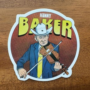 Puede incluir: Una pegatina con una ilustración de Kenny Baker tocando el violín. La imagen muestra a un hombre con traje azul, corbata amarilla y sombrero de vaquero. El texto "KENNY BAKER" está en letras amarillas sobre fondo rojo.