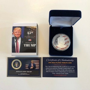 May include: A 24K gold-plated tribute coin featuring a portrait of Donald J. Trump, the 45th President of the United States. The coin is in a blue velvet box with a certificate of authenticity. The certificate states that the coin is a privately minted non-monetary tribute coin.