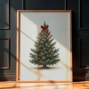 May include: A framed print of a Christmas tree with a red bow. The tree is decorated with small lights. The print is in a wooden frame and leans against a dark wall. The print is in a wooden frame.