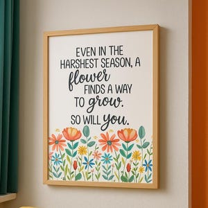 May include: A framed print with the text "EVEN IN THE HARSHEST SEASON, A flower FINDS A WAY TO grow. SO WILL you." The print features a floral border with orange, red, blue, and yellow flowers. The frame is light brown.