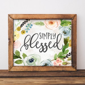 May include: A framed watercolor print with a floral wreath and the text "SIMPLY blessed" in black calligraphy.