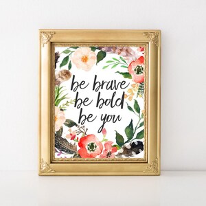May include: A framed print with a floral wreath and the text "be brave be bold be you".