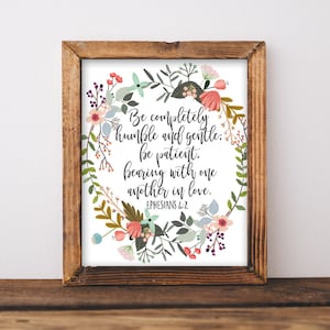 May include: A framed print with a floral wreath design and a quote from Ephesians 4:2. The quote reads "Be completely humble and gentle: be patient, bearing with one another in love."