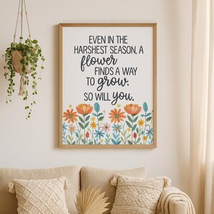 May include: A framed print with the text "EVEN IN THE HARSHEST SEASON, A flower FINDS A WAY TO grow. SO WILL you." The print features a floral border with orange, yellow, and blue flowers. The frame is a light brown color.