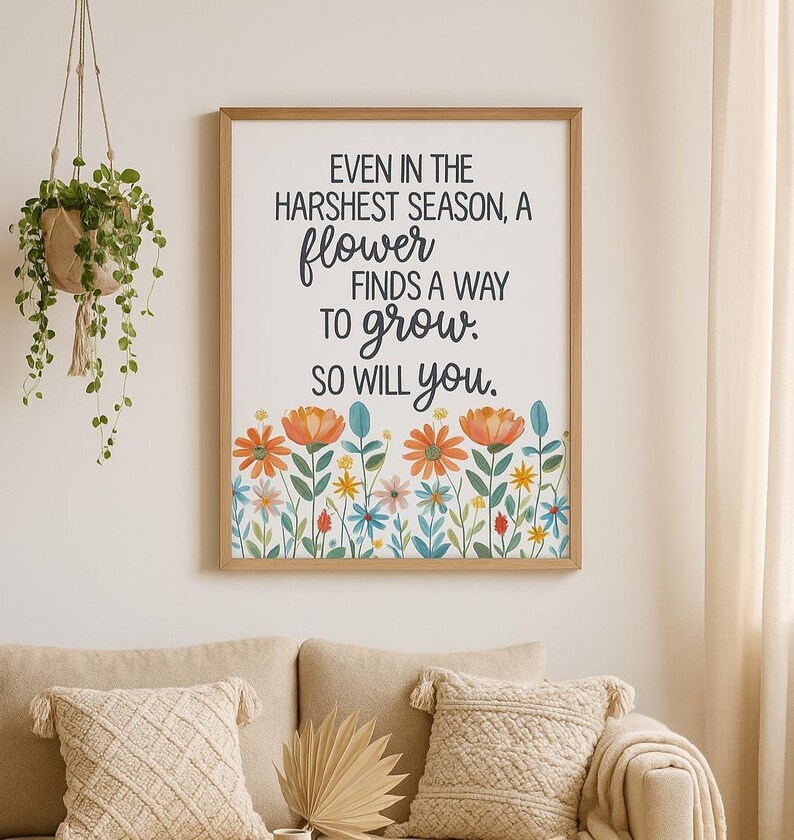 May include: A framed print with the text "EVEN IN THE HARSHEST SEASON, A flower FINDS A WAY TO grow. SO WILL you." The print features a floral border with orange, yellow, and blue flowers. The frame is a light brown color.
