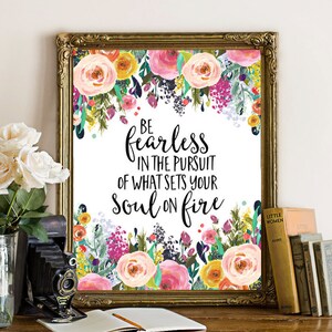 May include: A floral print with a white background and gold frame. The print features a quote that reads "Be fearless in the pursuit of what sets your soul on fire."