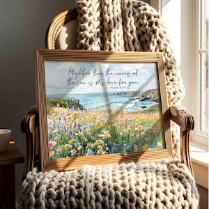 Könnte beinhalten: Ein rechteckiger gerahmter Druck mit einer Küstenlandschaft, einem Feld aus bunten Wildblumen im Vordergrund und dem Ozean im Hintergrund. Der Text lautet: Mightier than the waves of the sea is His love for you. Psalm 93:4.