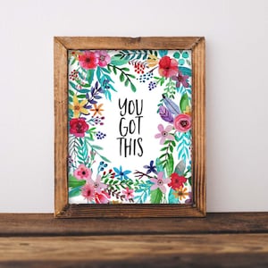 May include: A framed print featuring a watercolour floral wreath surrounding the text "YOU GOT THIS". The flowers are in shades of pink, purple, blue, yellow, and red.