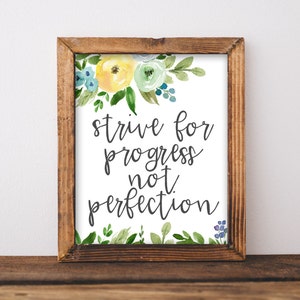 Puede incluir: Una impresión enmarcada con un diseño floral de acuarela en tonos amarillos, verdes y azules. La impresión presenta el texto "strive for progress not perfection".