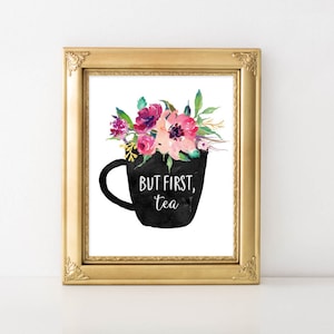 Puede incluir: Una taza de té negra con un arreglo floral de flores de acuarela rosa, púrpura y verde. El texto "But first, tea" está escrito en la taza de té.