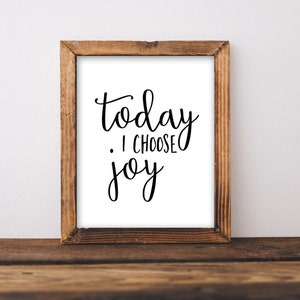 Puede incluir: Una impresión enmarcada con el texto "today I choose joy" en caligrafía negra sobre fondo blanco. El marco es de madera marrón.