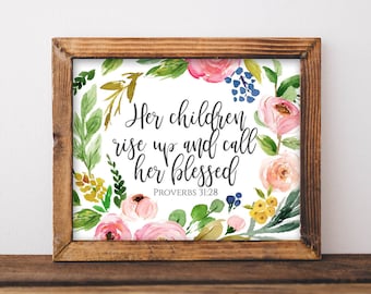 Pode incluir: Uma impressão emoldurada com um design floral em aquarela e a citação "Seus filhos se levantam e a chamam de abençoada" com a referência bíblica "Provérbios 31:28".