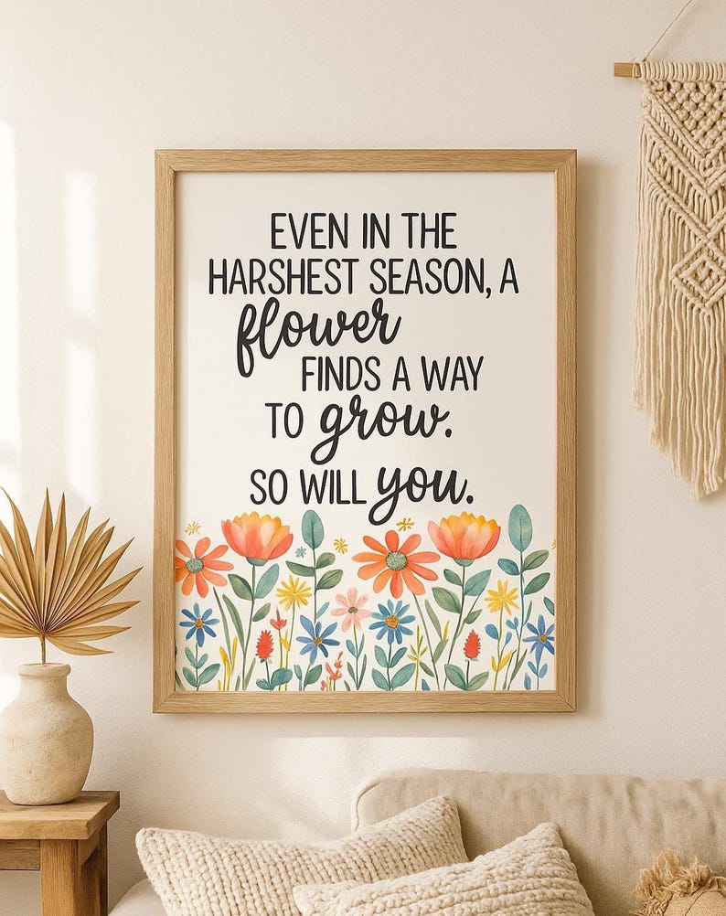 May include: A framed print with the quote "EVEN IN THE HARSHEST SEASON, A flower FINDS A WAY TO grow. SO WILL you." The print features a floral border with orange, blue, and yellow flowers. The frame is made of light-colored wood.