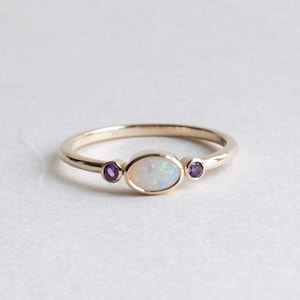Peut inclure: Une bague en or avec une opale blanche et deux petites pierres d'améthyste violettes.