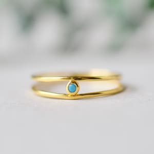 May include: A gold ring with a thin band and a small turquoise stone in the center.