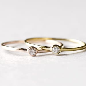 May include: Two simple gold rings with a single small diamond on each. One ring is rose gold and the other is yellow gold.