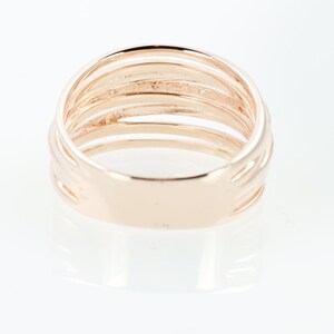 May include: A gold-toned ring with multiple bands, creating a layered effect. The ring is smooth and polished.