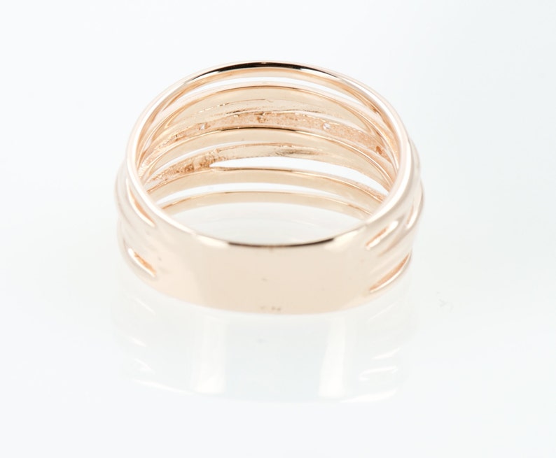 May include: A gold-toned ring with multiple bands, creating a layered effect. The ring is smooth and polished.