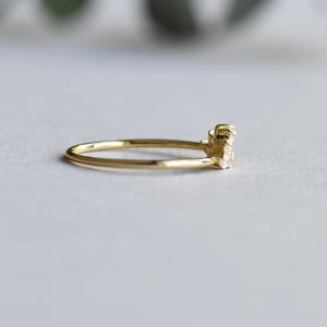 May include: A delicate gold band ring with a cluster of small, clear gemstones set in the center.