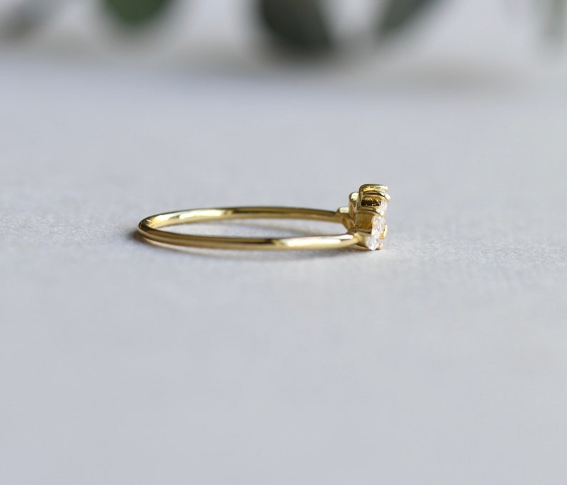 May include: A delicate gold band ring with a cluster of small, clear gemstones set in the center.