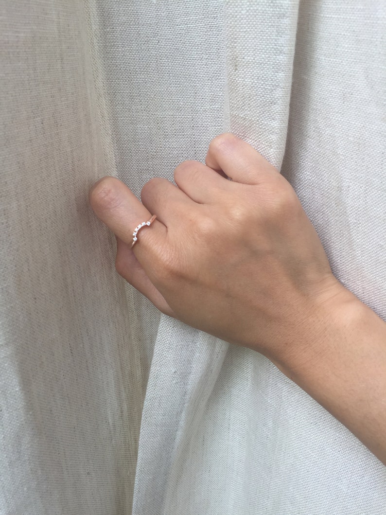 May include: A delicate gold ring with a row of small, clear stones set in a curved shape.