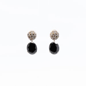 May include: A pair of silver earrings with black oval-shaped stones and a round cluster of marcasite stones.