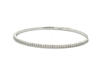 May include: A delicate white gold bangle bracelet with a single row of pave set diamonds.