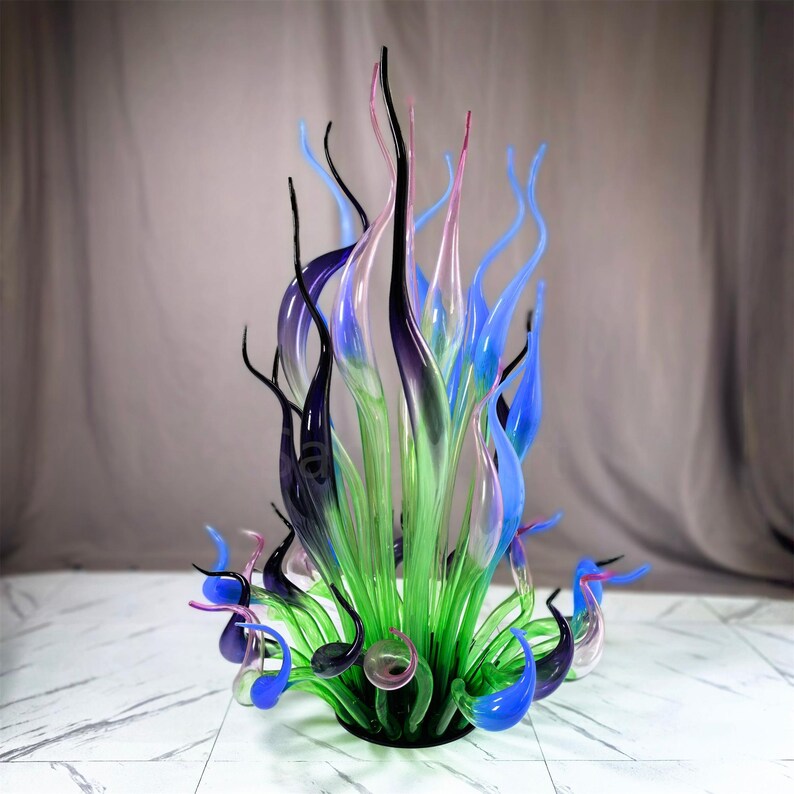 Large hand-blown glass garden sculpture featuring organic flame shapes in green, blue, and purple hues, perfect for elevating outdoor patios, backyard landscapes, and garden focal points