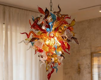 May include: A vibrant glass chandelier featuring a cascade of colourful glass elements in shades of red, orange, yellow, and blue. The light fixture hangs from a chain, designed to provide ambient lighting. The design is artistic and decorative, suitable for interior spaces.