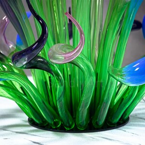 Close-up view of the lush green glass base and stems, showing the translucent texture and natural seaweed-inspired form of the hand-blown sculpture