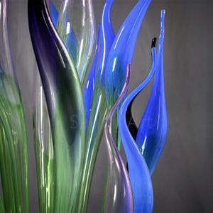 Macro shot of the slender, curved tips of the glass reeds, highlighting the thin, delicate glass structure and the way light interacts with the glossy surface