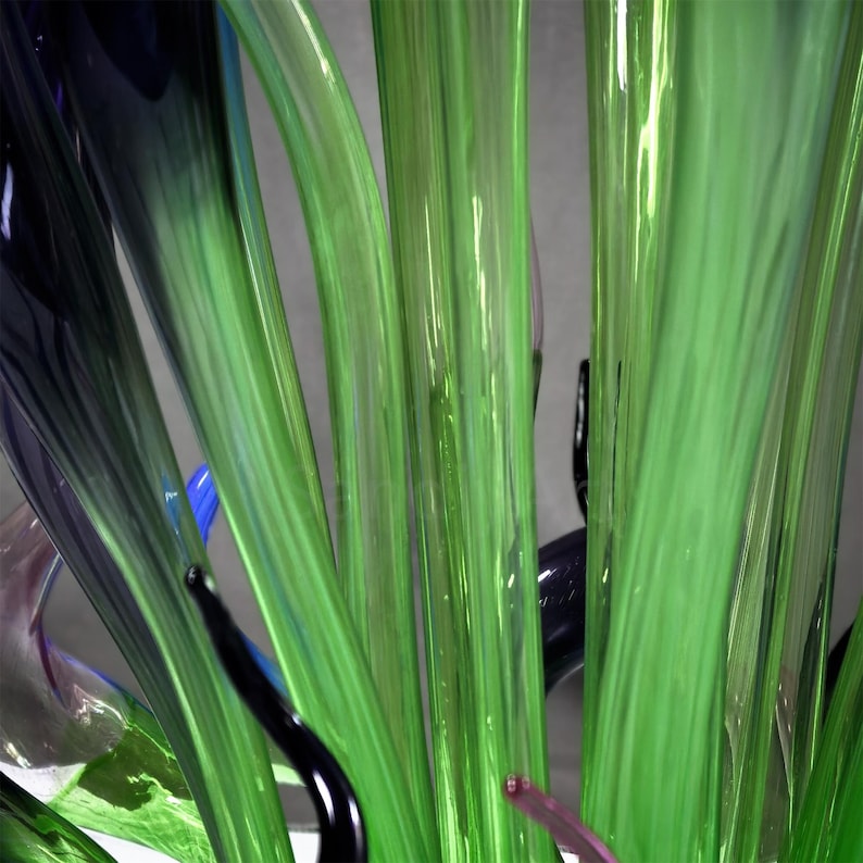 Close-up of overlapping green, blue, and purple glass forms, emphasizing the layered, coral-like texture and depth of the hand-blown sculpture