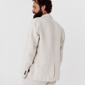 May include: A light beige linen blazer with a single button closure. The blazer has a relaxed fit and a slightly textured fabric.