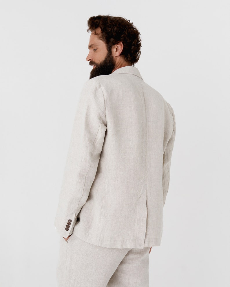 May include: A light beige linen blazer with a single button closure. The blazer has a relaxed fit and a slightly textured fabric.