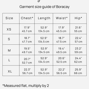 May include: A black and white garment size guide chart for Magic Linen Boracay. The table lists sizes XS through XL with corresponding chest, length, waist, and hip measurements in both inches and centimeters. A note states: *Measured flat, multiply by 2.