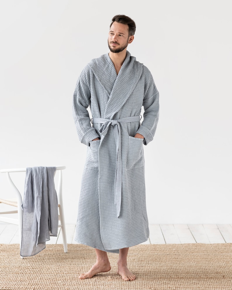 May include: A gray waffle weave robe with a hood and a self-tie belt. The robe is made of a soft, absorbent material and is perfect for lounging around the house.