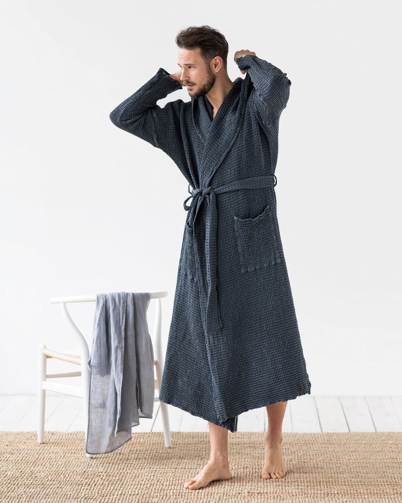 May include: A dark blue waffle weave robe with a hood and a tie belt. The robe is made of a soft, comfortable fabric and has a relaxed fit.