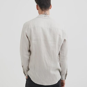 Pu&ograve; includere: Camicia beige chiaro a maniche lunghe con colletto button-down. La camicia &egrave; realizzata in un tessuto strutturato e ha una vestibilit&agrave; rilassata. Il retro della camicia &egrave; visibile, mostrando lo sprone e l'orlo curvo. Le maniche sono abbottonate ai polsini.