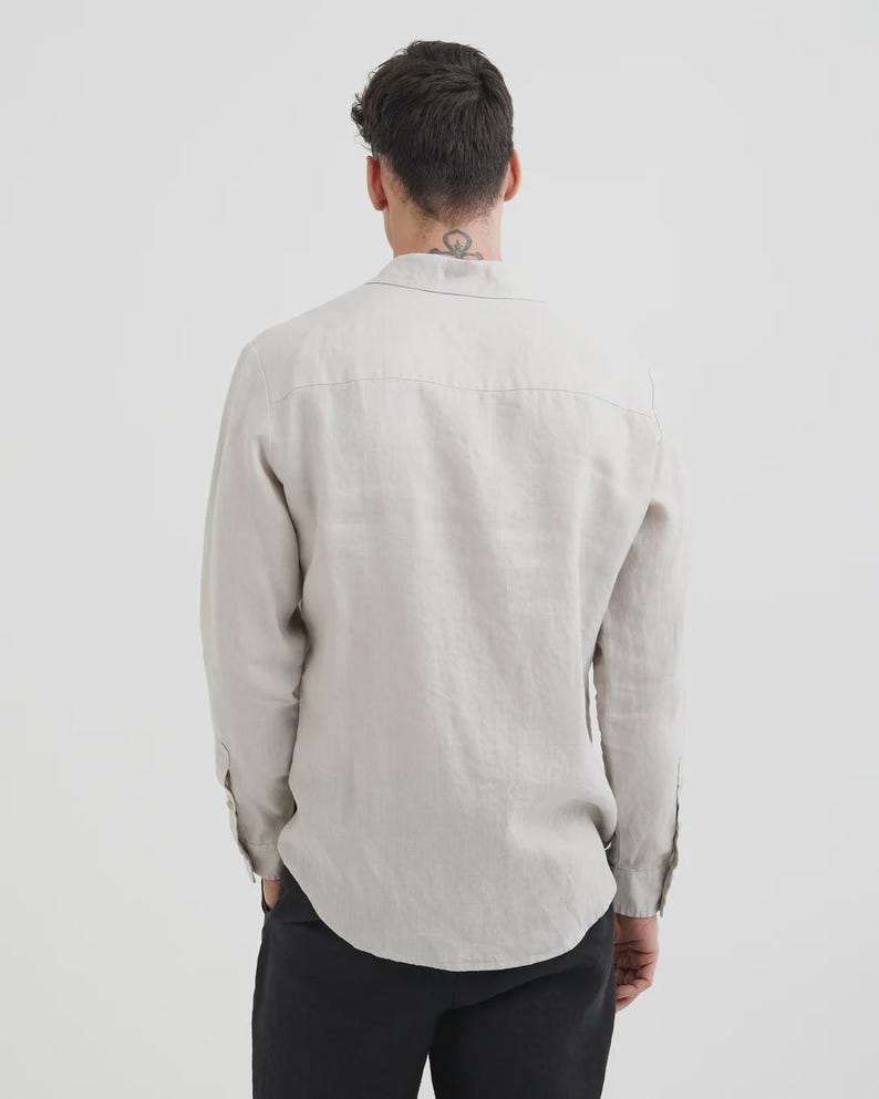 Pu&ograve; includere: Camicia beige chiaro a maniche lunghe con colletto button-down. La camicia &egrave; realizzata in un tessuto strutturato e ha una vestibilit&agrave; rilassata. Il retro della camicia &egrave; visibile, mostrando lo sprone e l'orlo curvo. Le maniche sono abbottonate ai polsini.