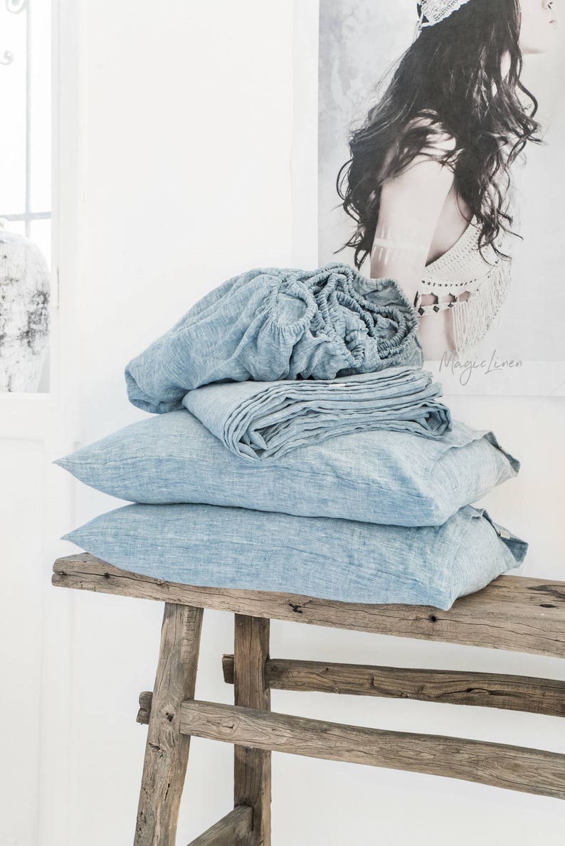 Rustic raw wood bench piled with beautiful chambray linen bedding - beachy serene indeed!