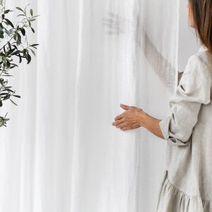 May include: A white linen curtain with a woman's hand reaching out to touch it. The text "Magic Linen" is visible in the bottom left corner of the image.