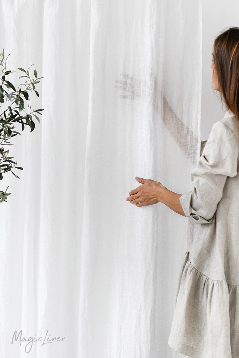 May include: A white linen curtain with a woman's hand reaching out to touch it. The text "Magic Linen" is visible in the bottom left corner of the image.