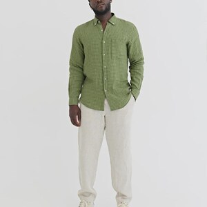 K&ouml;nnte beinhalten: Ein gr&uuml;nes kariertes Hemd, eine beige Hose und wei&szlig;e Turnschuhe. Das Hemd hat eine Brusttasche. Die Hose ist hellbeige. Die Turnschuhe sind wei&szlig; mit beigen Sohlen. Ein l&auml;ssiger, stilvoller Look.