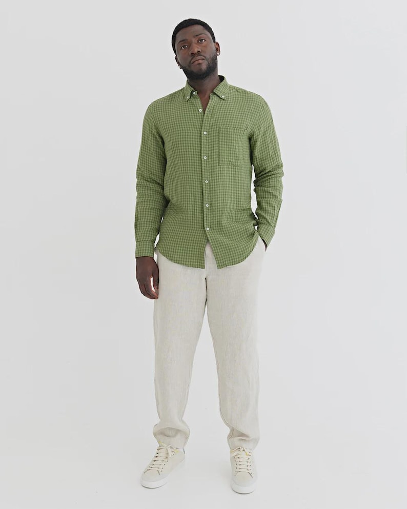 K&ouml;nnte beinhalten: Ein gr&uuml;nes kariertes Hemd, eine beige Hose und wei&szlig;e Turnschuhe. Das Hemd hat eine Brusttasche. Die Hose ist hellbeige. Die Turnschuhe sind wei&szlig; mit beigen Sohlen. Ein l&auml;ssiger, stilvoller Look.