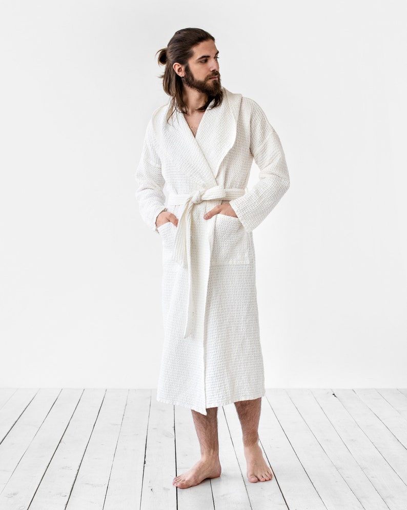 May include: A white waffle weave robe with a shawl collar and a tie belt. The robe is made of a soft, absorbent material and is perfect for lounging around the house.