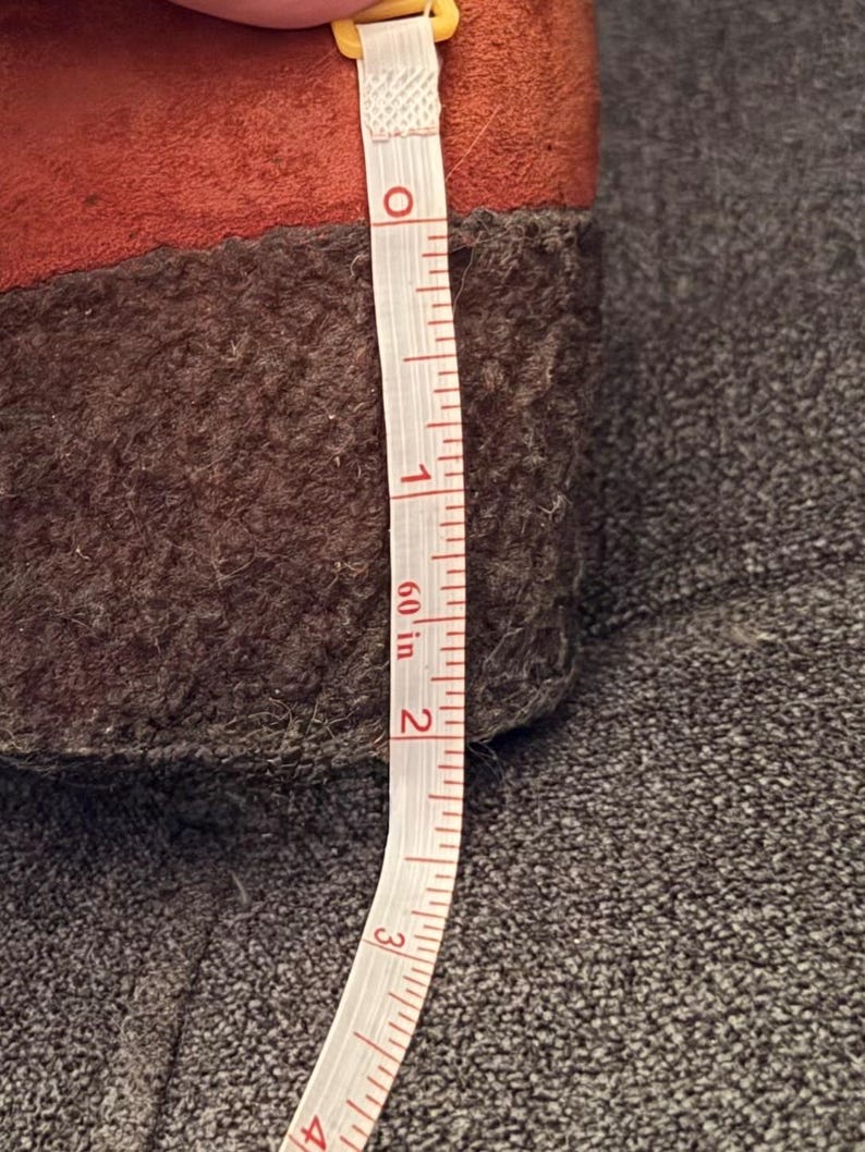Puede incluir: Primer plano de un zapato marr&oacute;n y naranja con suela marr&oacute;n oscuro. Una cinta m&eacute;trica blanca muestra que la altura del zapato es de aproximadamente 5 cm. El zapato est&aacute; sobre una superficie gris.
