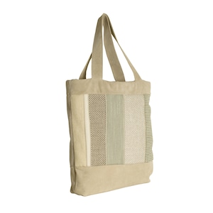 Può includere: Una borsa tote beige con un motivo intrecciato in tonalità di verde e bianco.